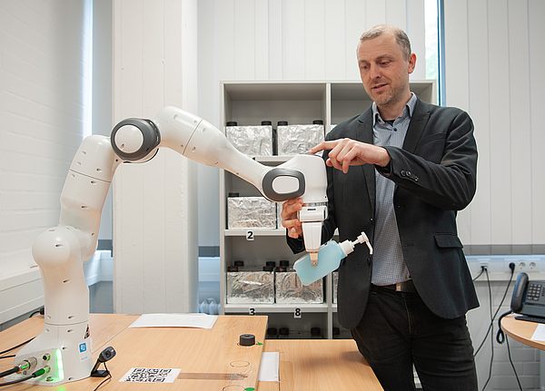 NaMeKI-Projektinitiator Prof. Reinhardt interagiert mit einem Kobot-Roboterarm, Foto: Ernst